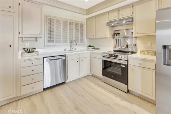 a kitchen with cabinets stainless steel appliances and wooden floor