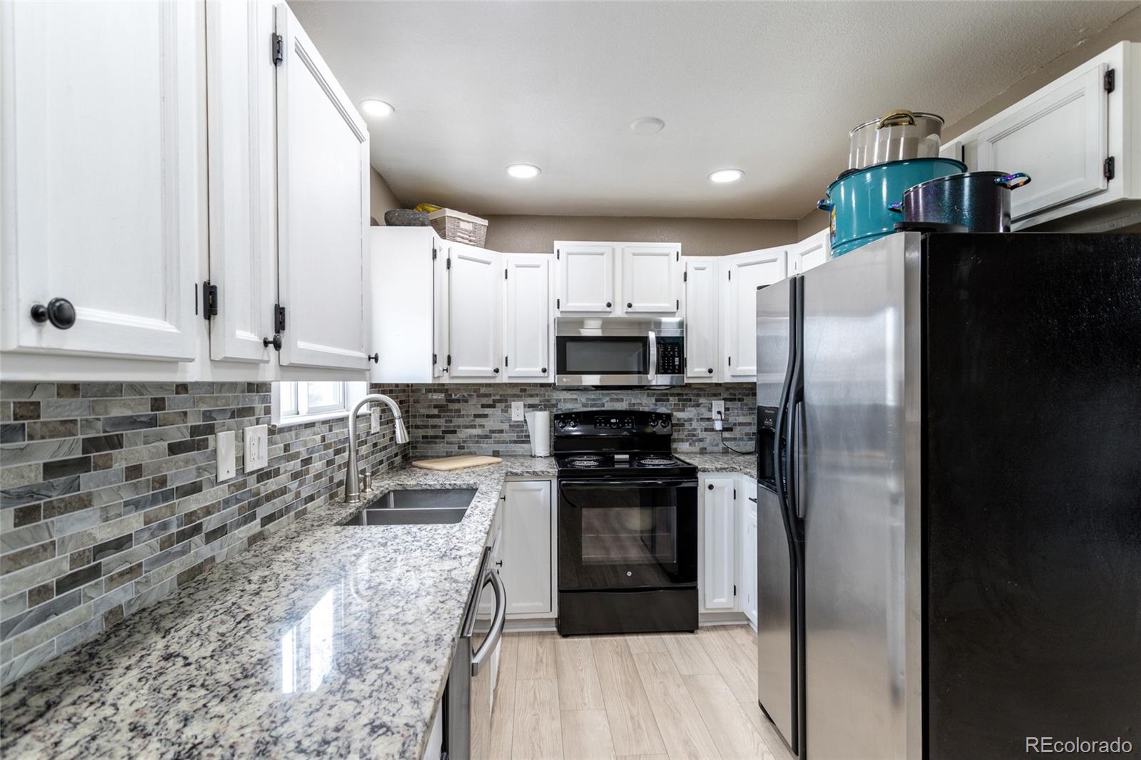 3192 West 3rd Street Road Greeley, CO 80631 - Photo 9 of 31 a kitchen with granite countertop a refrigerator stove and sink