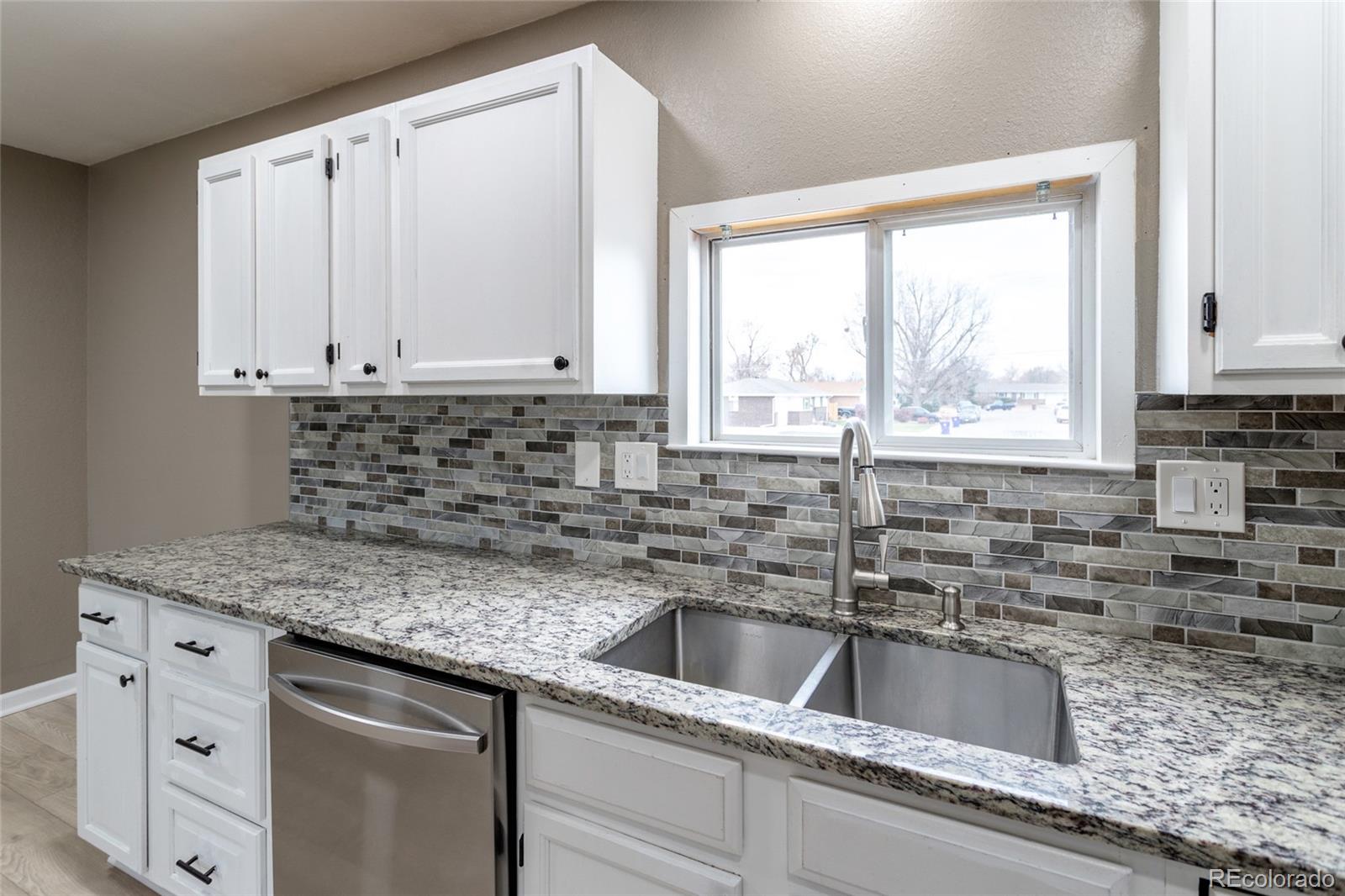 3192 West 3rd Street Road Greeley, CO 80631 - Photo 10 of 31 a kitchen with granite countertop a sink window and cabinets