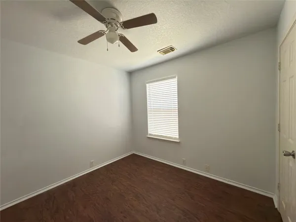 an empty room with a window and a fan