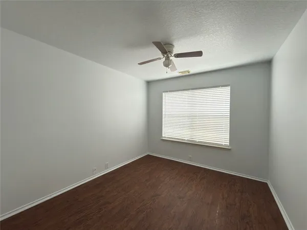an empty room with wooden floor ceiling fan and windows