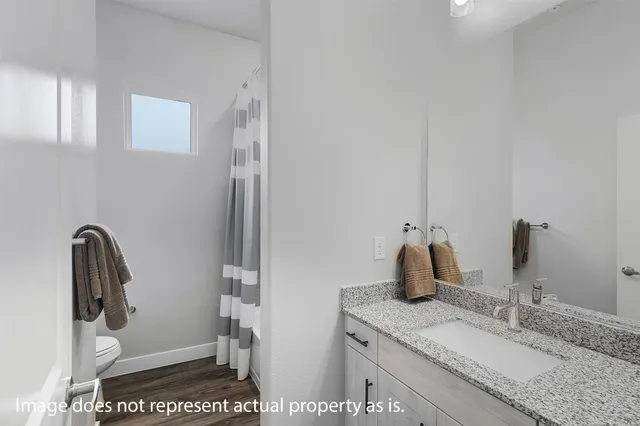 a bathroom with a granite countertop sink a toilet and a mirror