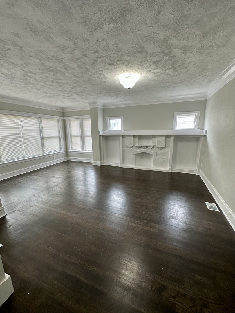 7828 South Carpenter Street Chicago, IL 60620 - Photo 2 of 18 an empty room with wooden floor and windows
