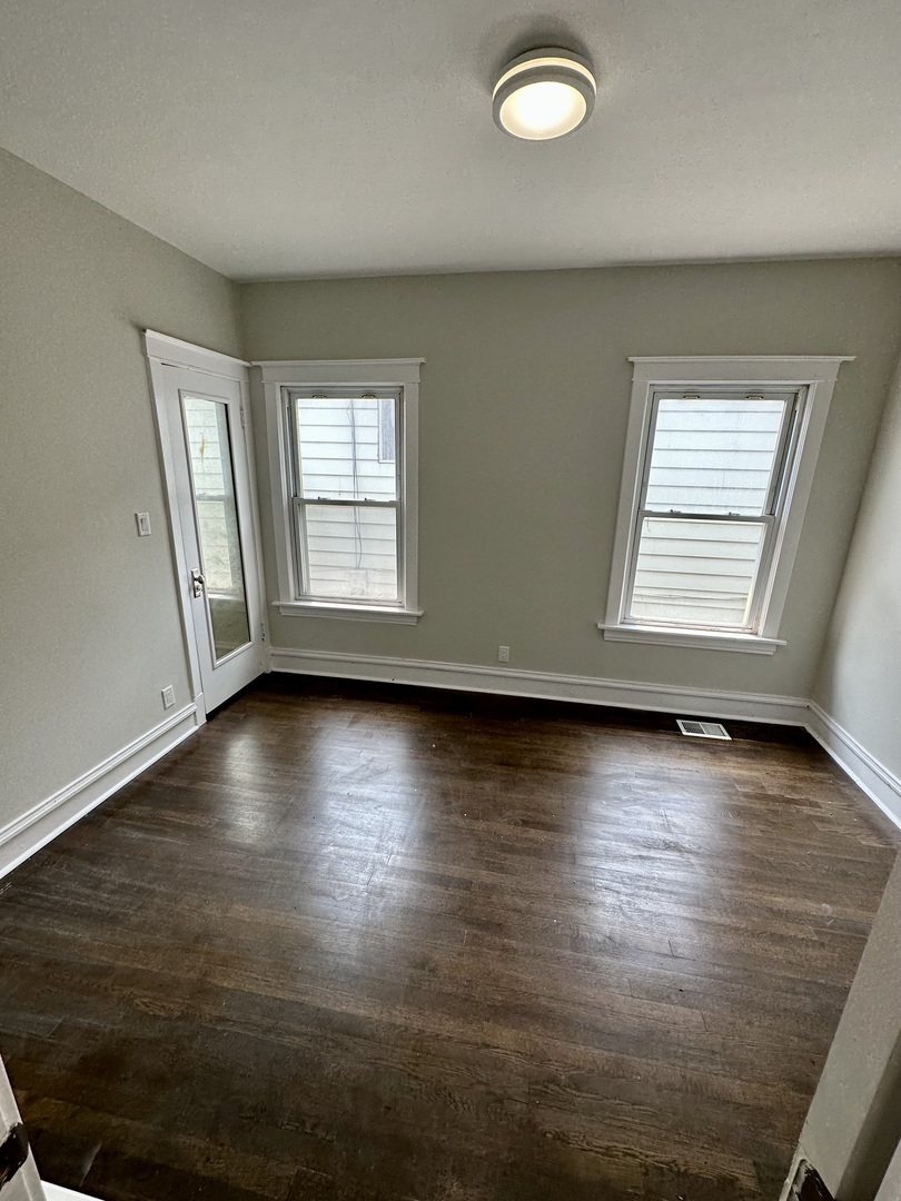 7828 South Carpenter Street Chicago, IL 60620 - Photo 6 of 18 an empty room with wooden floor and windows