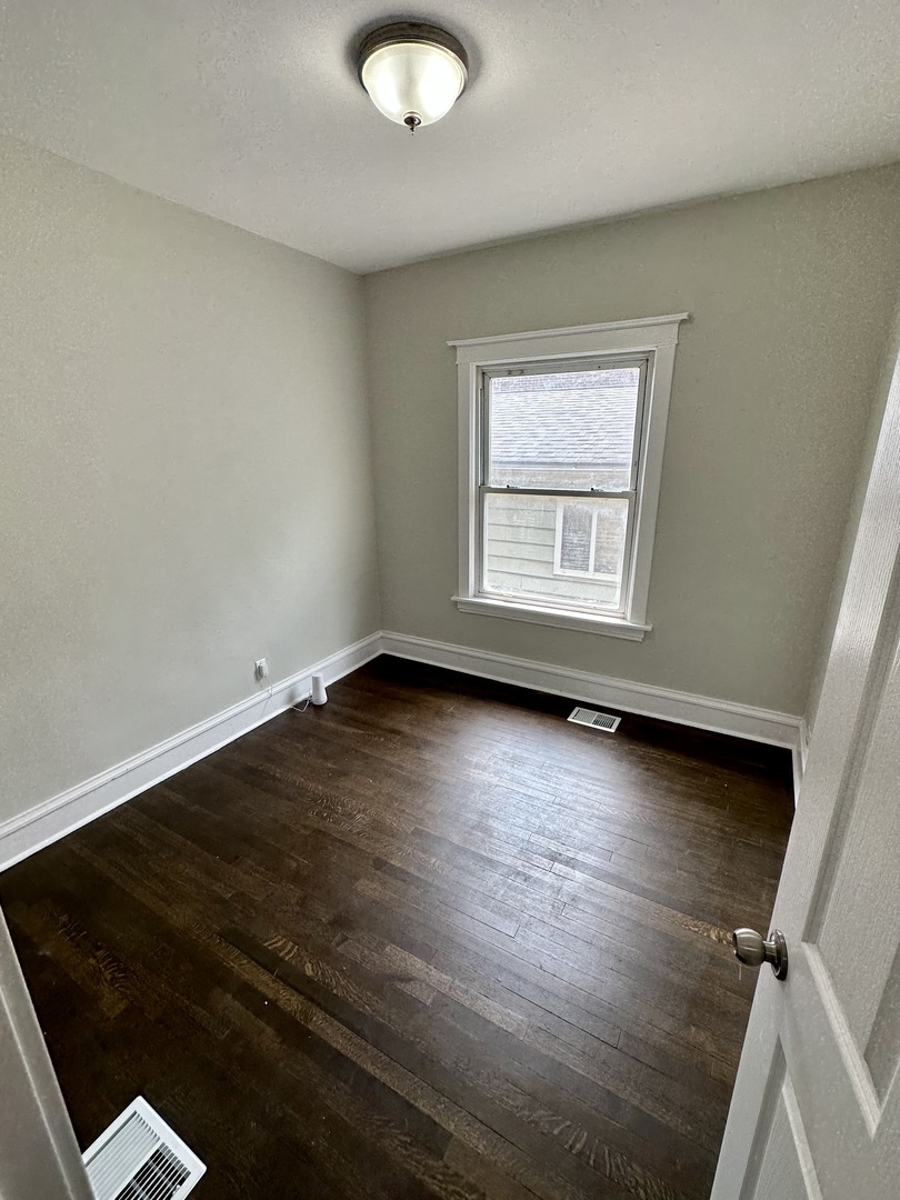 7828 South Carpenter Street Chicago, IL 60620 - Photo 8 of 18 an empty room with wooden floor and windows