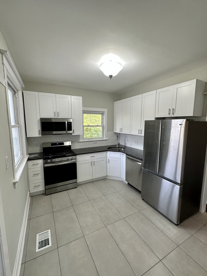 7828 South Carpenter Street Chicago, IL 60620 - Photo 10 of 18 a kitchen with granite countertop a refrigerator and a stove top oven