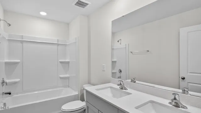a bathroom with a bathtub shower sink vanity mirror and toilet