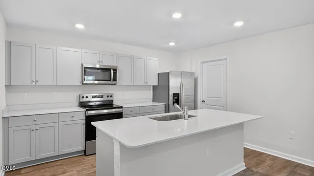 a kitchen with a sink a stove a refrigerator and white cabinets