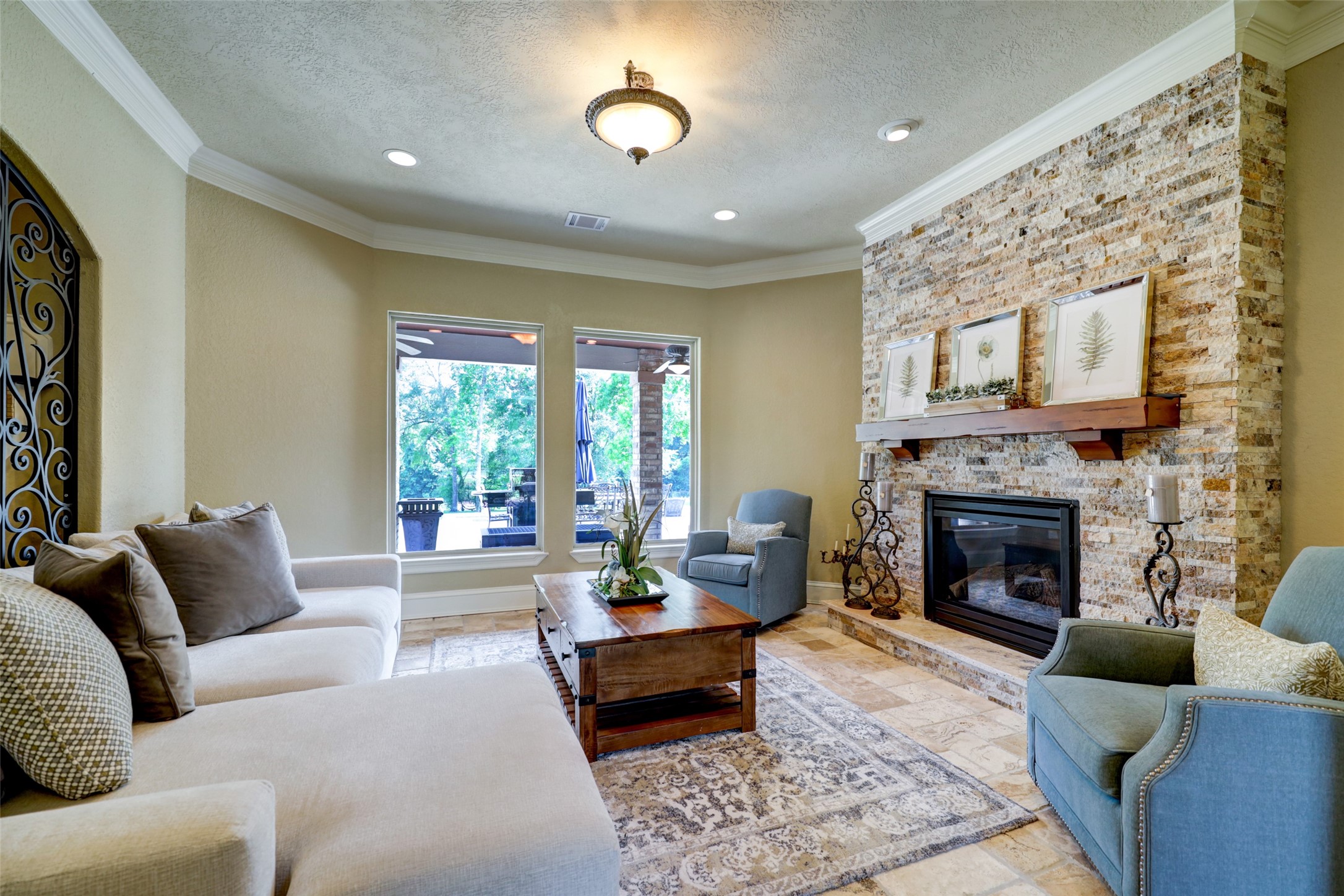 4434 Chateau Creek Way Spring, TX 77386 - Photo 20 of 34 This inviting living room features a cozy stone fireplace, elegant crown molding, and ample natural light from large windows. Neutral tones and comfortable seating create a warm, welcoming ambiance.