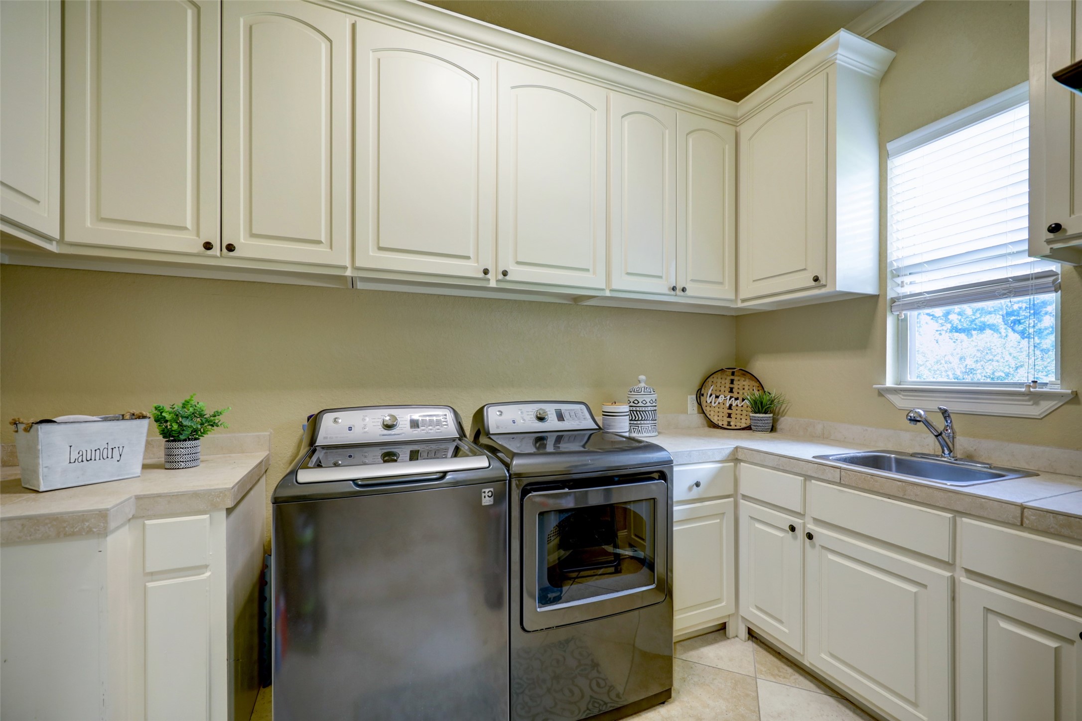 4434 Chateau Creek Way Spring, TX 77386 - Photo 34 of 34 This laundry room features modern appliances, ample cabinetry for storage, and a convenient sink area. Natural light streams in through a window, creating a bright and functional space.