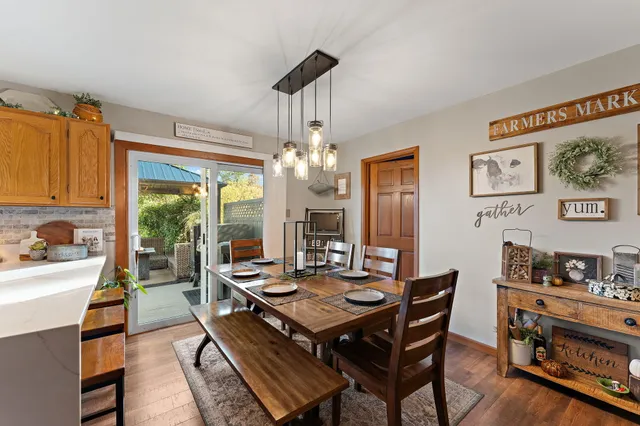 a dining room with wooden floor a chandelier a wooden table and chairs