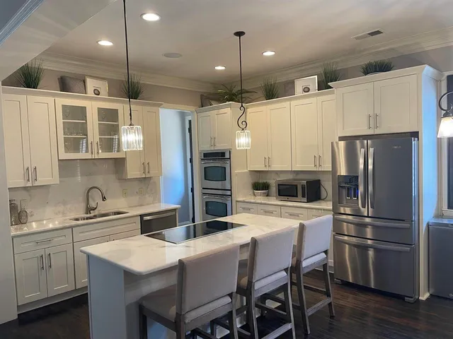 a kitchen with a refrigerator a sink a stove and chairs