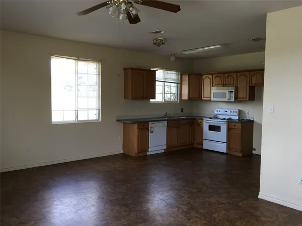 an open kitchen with granite countertop a stove top oven a sink and dishwasher with wooden floor