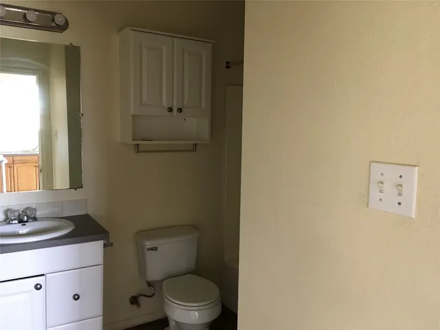 a bathroom with a toilet sink vanity and mirror