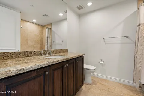 a bathroom with a granite countertop sink a toilet and a shower