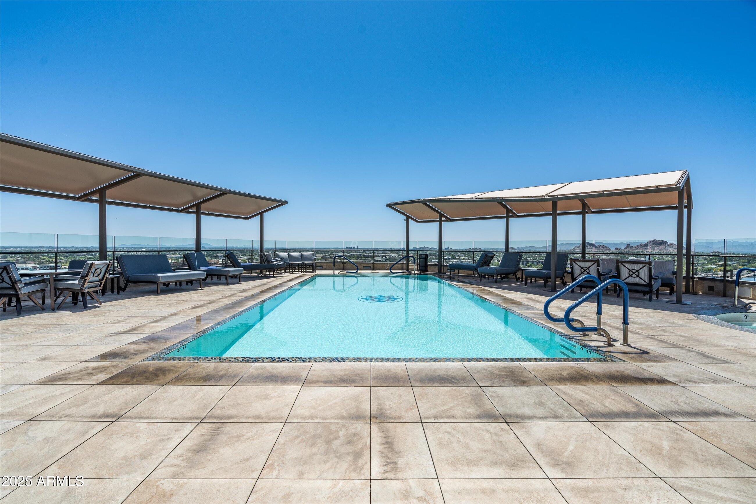 7175 East Camelback Road, Unit 510 Scottsdale, AZ 85251 - Photo 27 of 34 a swimming pool with lawn chairs under an umbrella