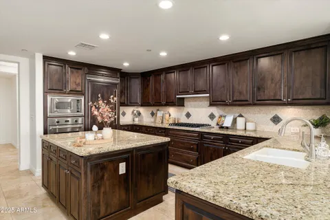 a kitchen with stainless steel appliances granite countertop a stove a sink dishwasher and a refrigerator with wooden cabinets