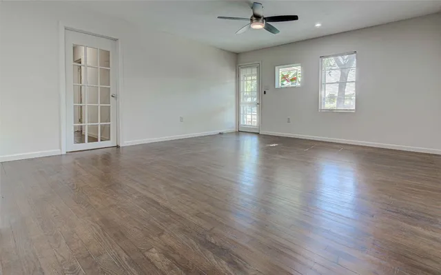 an empty room with wooden floor chandelier and windows