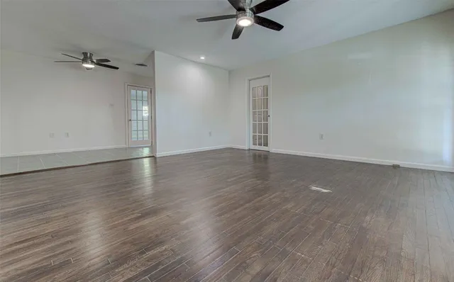 an empty room with wooden floor fan and windows