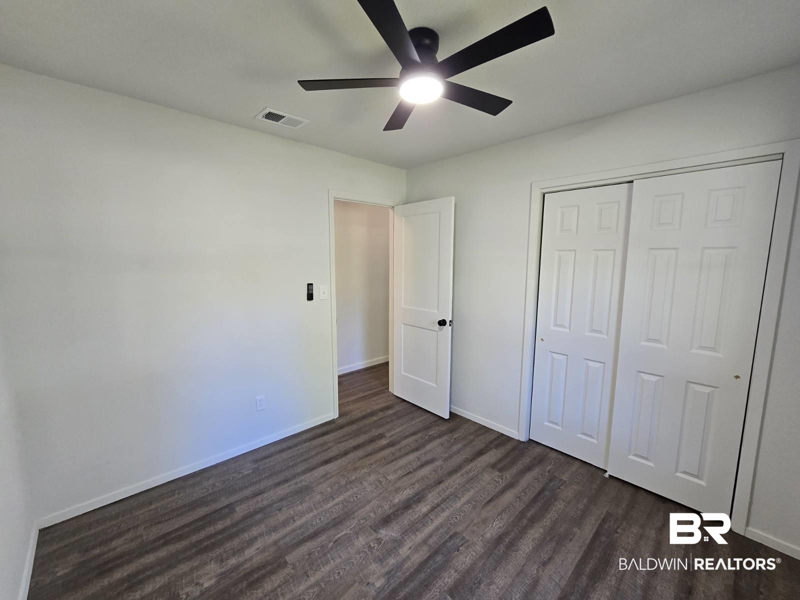 1404 Dailey Street Brewton, AL 36426 - Photo 14 of 25 Unfurnished bedroom with dark wood-style flooring, ceiling fan, and a closet