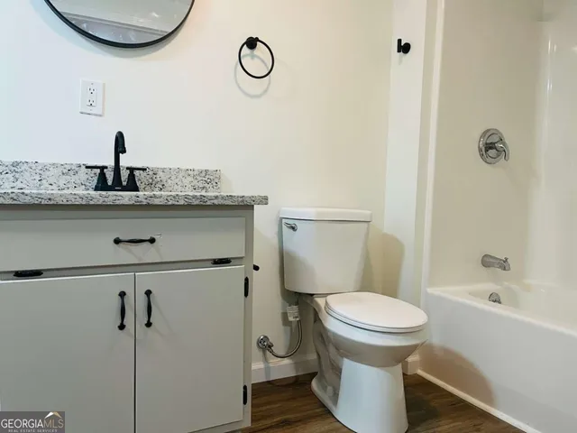 a bathroom with a granite countertop toilet sink and mirror