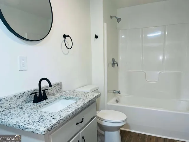 a bathroom with a granite countertop sink a toilet and a mirror
