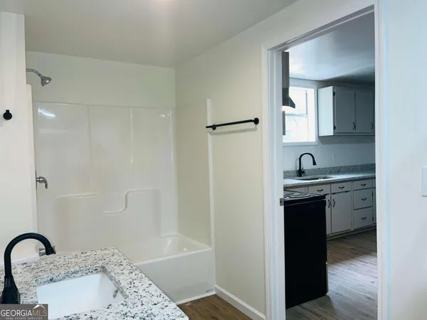 a bathroom with a granite countertop sink a toilet and bathtub