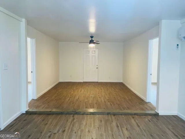 an empty room with wooden floor chandelier fan and windows