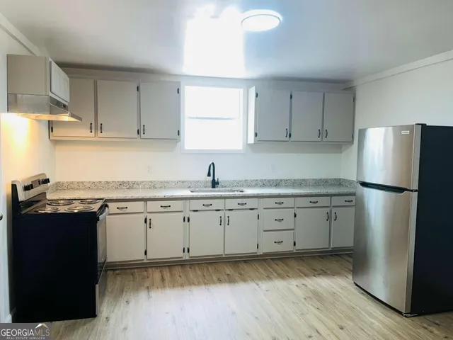 a kitchen with granite countertop cabinets appliances and a counter space