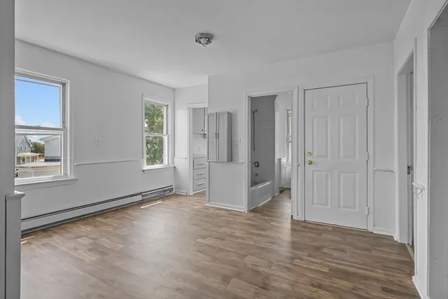 an empty room with wooden floor and windows