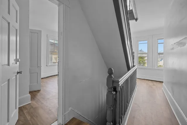a view of a hallway with wooden floor and stairs