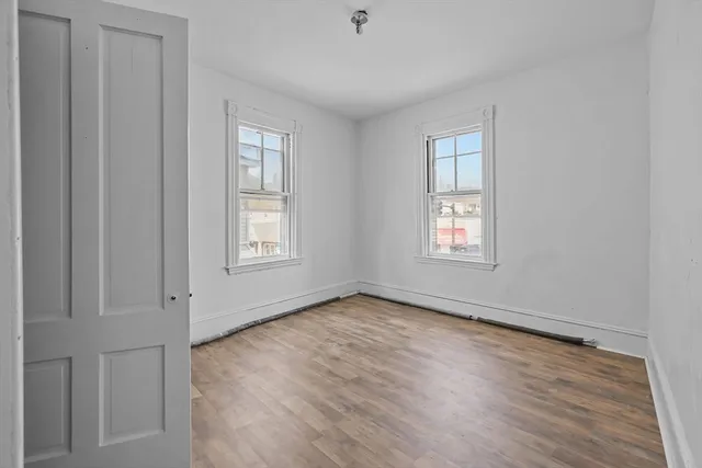 a view of an empty room with wooden floor and window