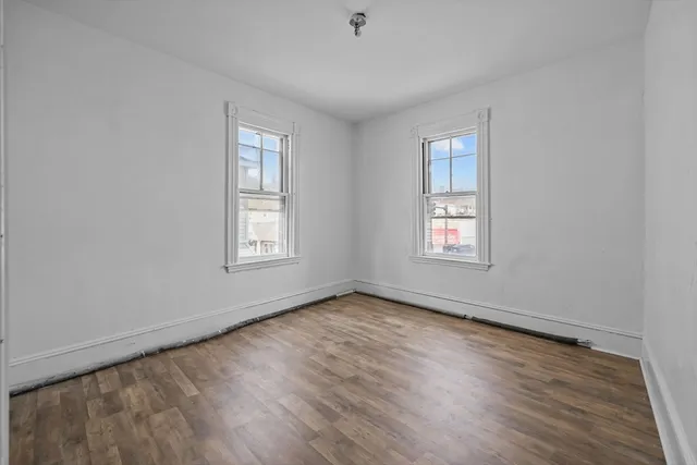 a view of an empty room with wooden floor and window