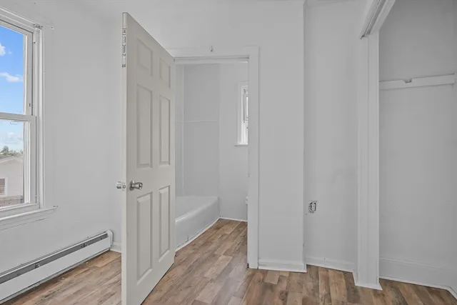 a view of a hallway with wooden floor and closet