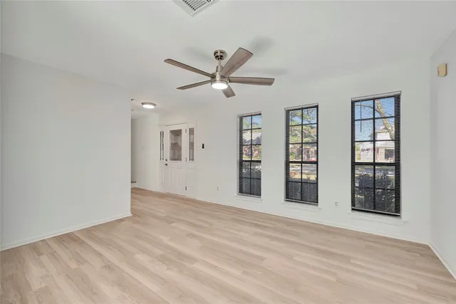 a view of an empty room with a window and wooden floor