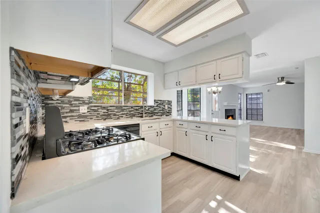 a kitchen with stainless steel appliances kitchen island granite countertop a stove a sink and white cabinets