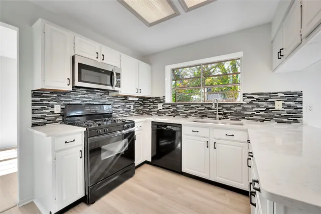 a kitchen with stainless steel appliances granite countertop a stove a sink and a microwave