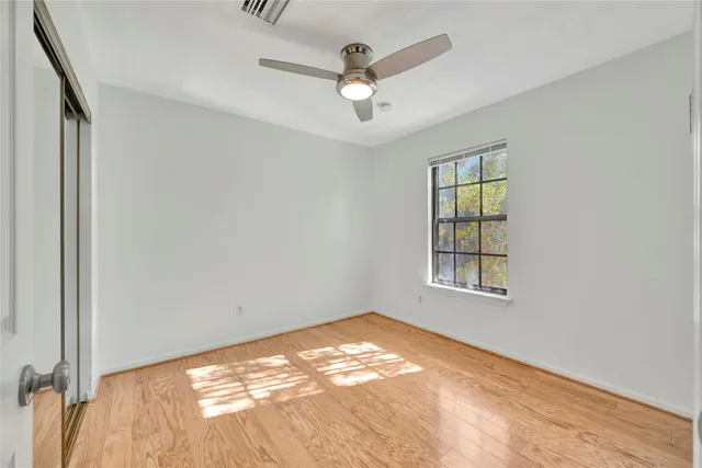 an empty room with windows and ceiling fan