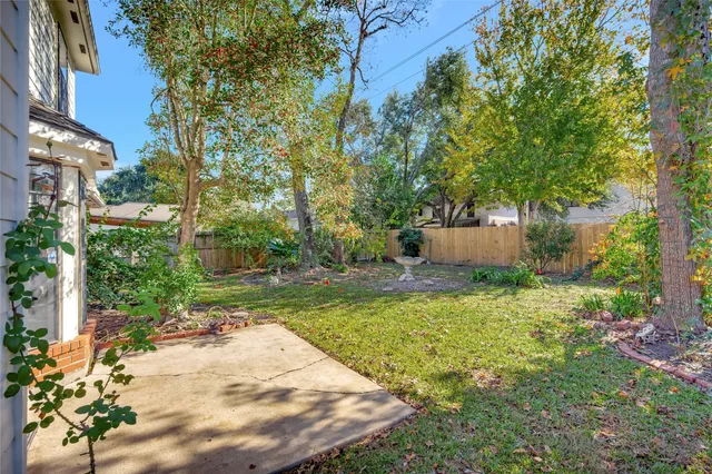 a backyard of a house with table and chairs plants and large trees
