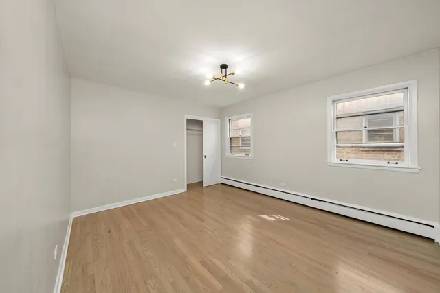 an empty room with windows and chandelier fan
