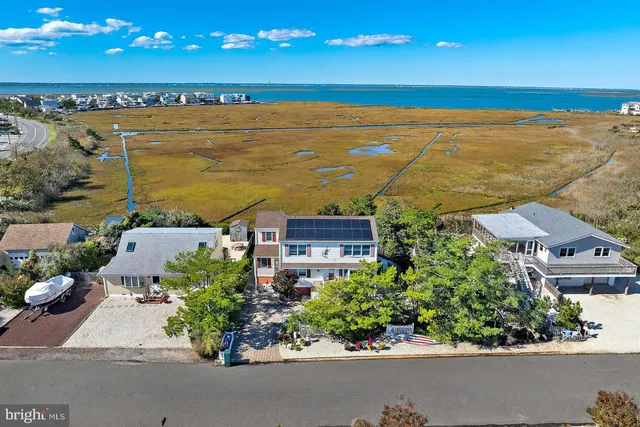 an aerial view of ocean and residential houses with outdoor space