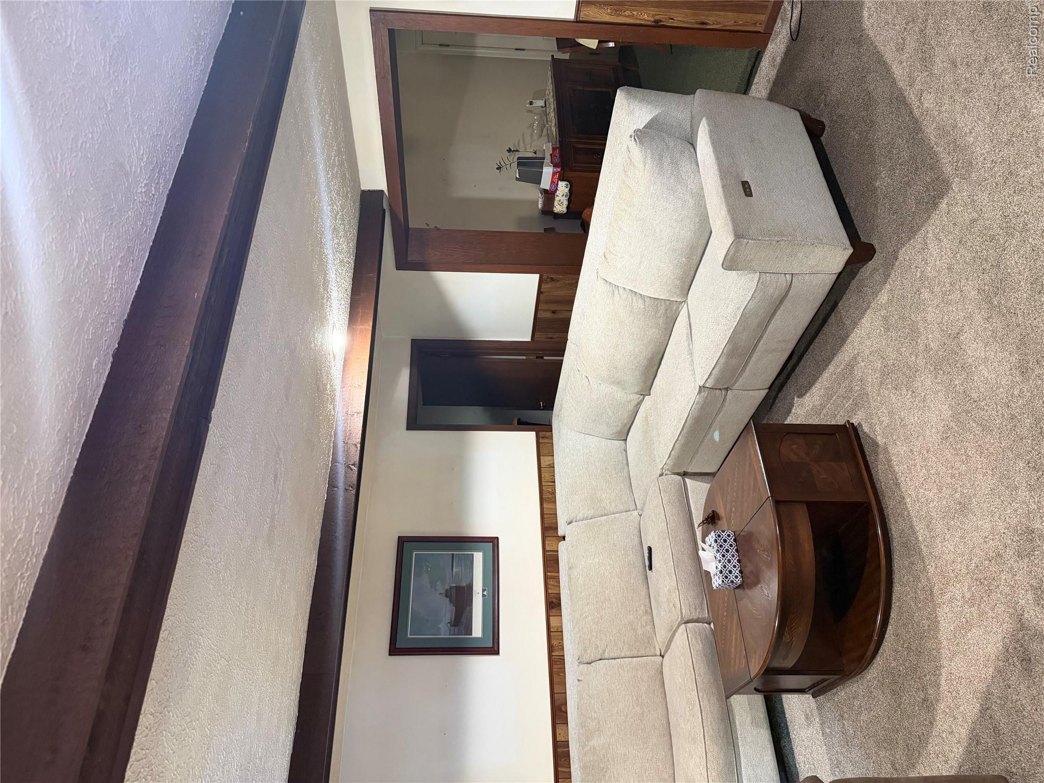 24934 23 Mile Road Macomb, MI 48042 - Photo 3 of 24 Carpeted living space featuring exposed wood ceiling beams, wood paneling, and a framed art piece