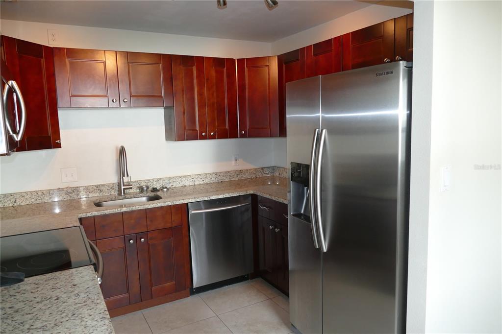 205 South McMullen Booth Road, Unit 203 Clearwater, FL 33759 - Photo 9 of 12 a kitchen with stainless steel appliances granite countertop a refrigerator and a sink