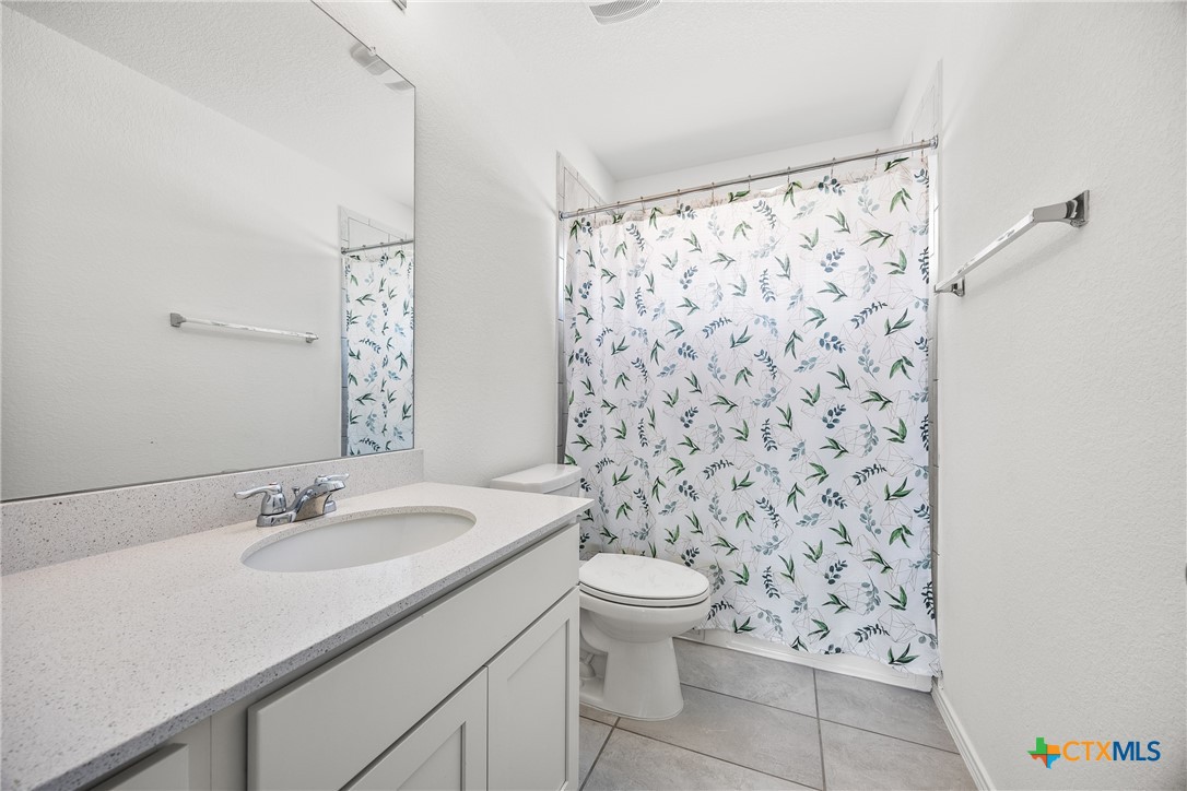 141 Rowdy Yates Way Jarrell, TX 76537 - Photo 19 of 32 a bathroom with a granite countertop sink a toilet and a mirror