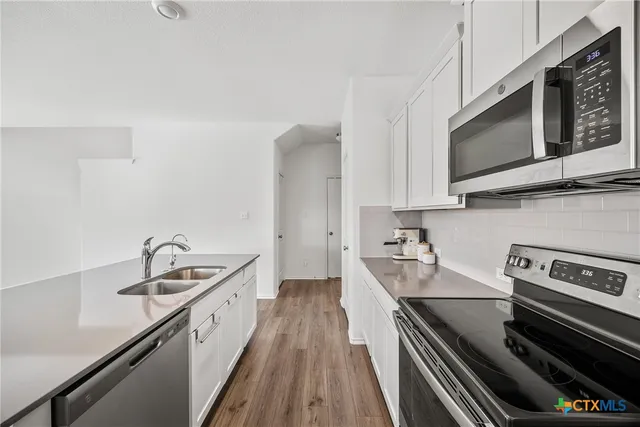 a kitchen with stainless steel appliances a sink a stove and cabinets