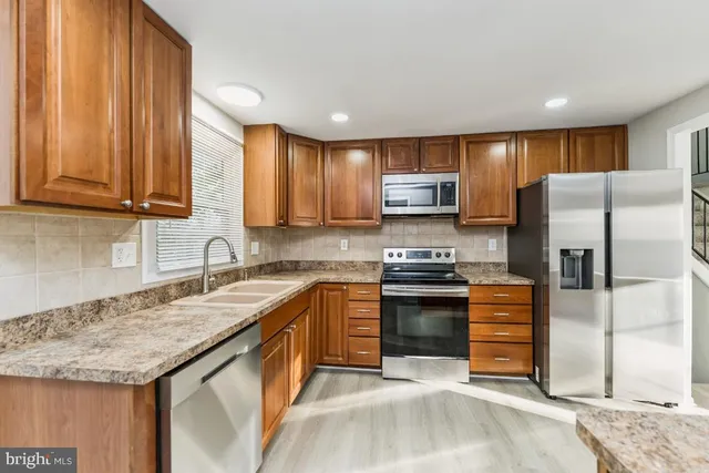 a kitchen with stainless steel appliances granite countertop a stove a sink and a refrigerator