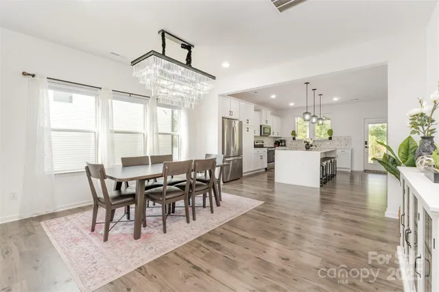 a dining room with furniture a chandelier and wooden floor