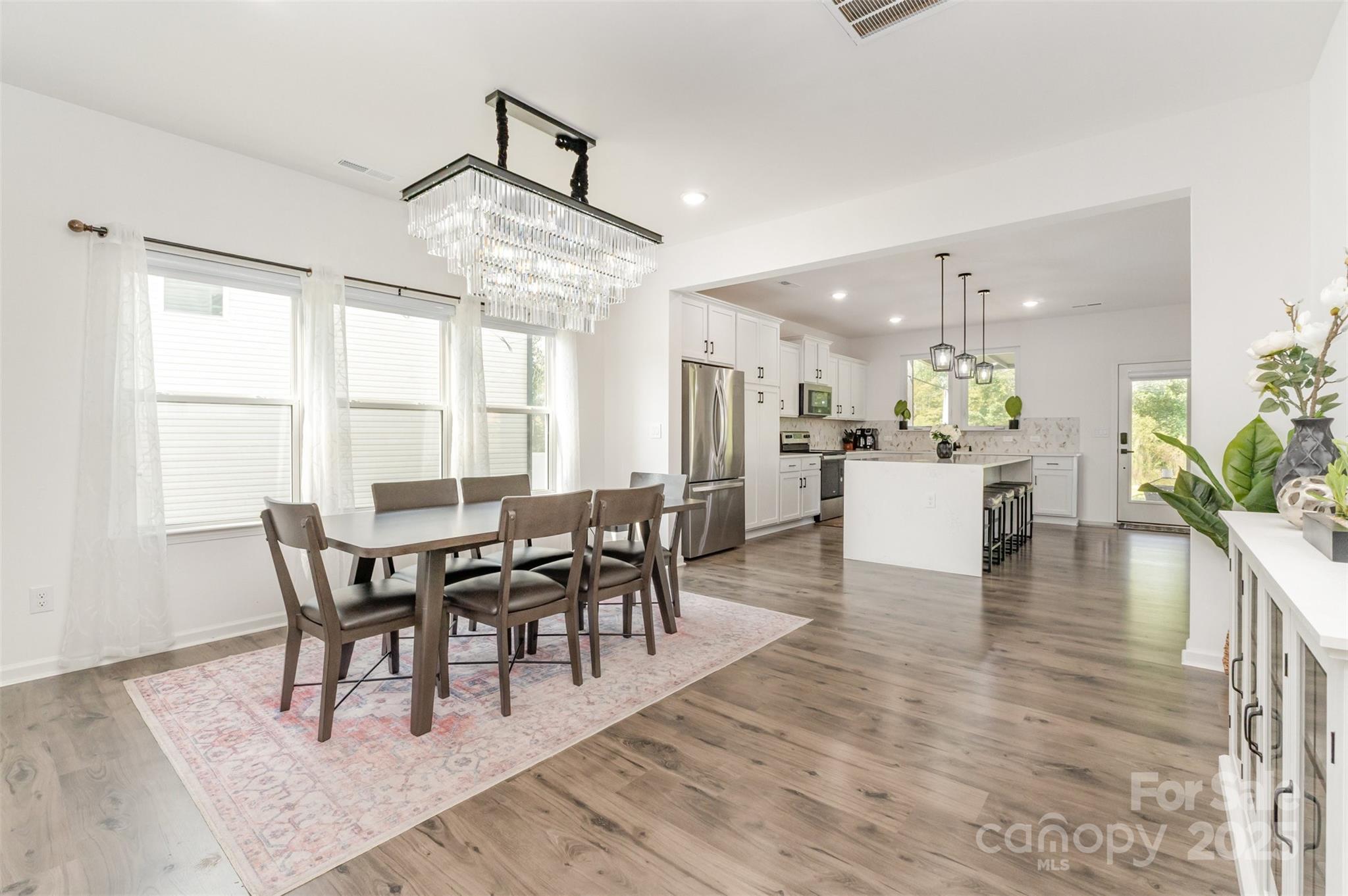 3127 Pinehills Wy. Mount Holly, NC 28120 - Photo 4 of 35 a dining room with wooden floor a chandelier a wooden table and chairs