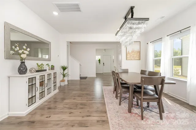 a kitchen with stainless steel appliances a dining table chairs refrigerator and sink