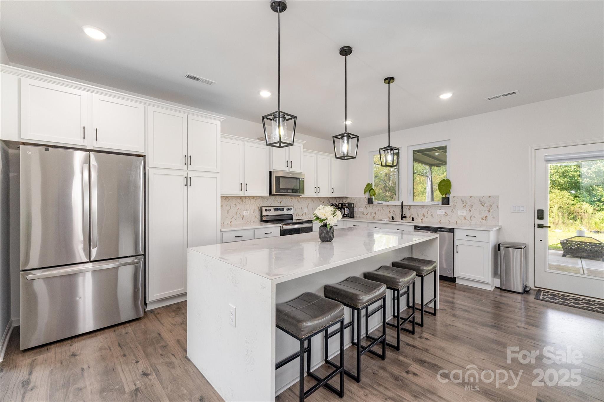 3127 Pinehills Wy. Mount Holly, NC 28120 - Photo 6 of 35 a kitchen with stainless steel appliances a dining table chairs refrigerator and sink